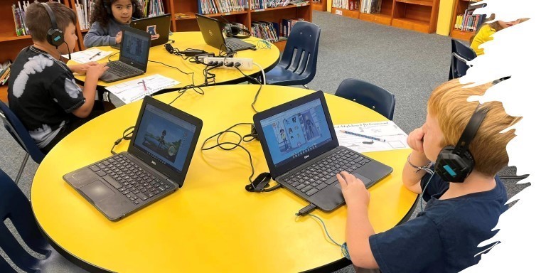 group of students at a table in the media center using laptops 